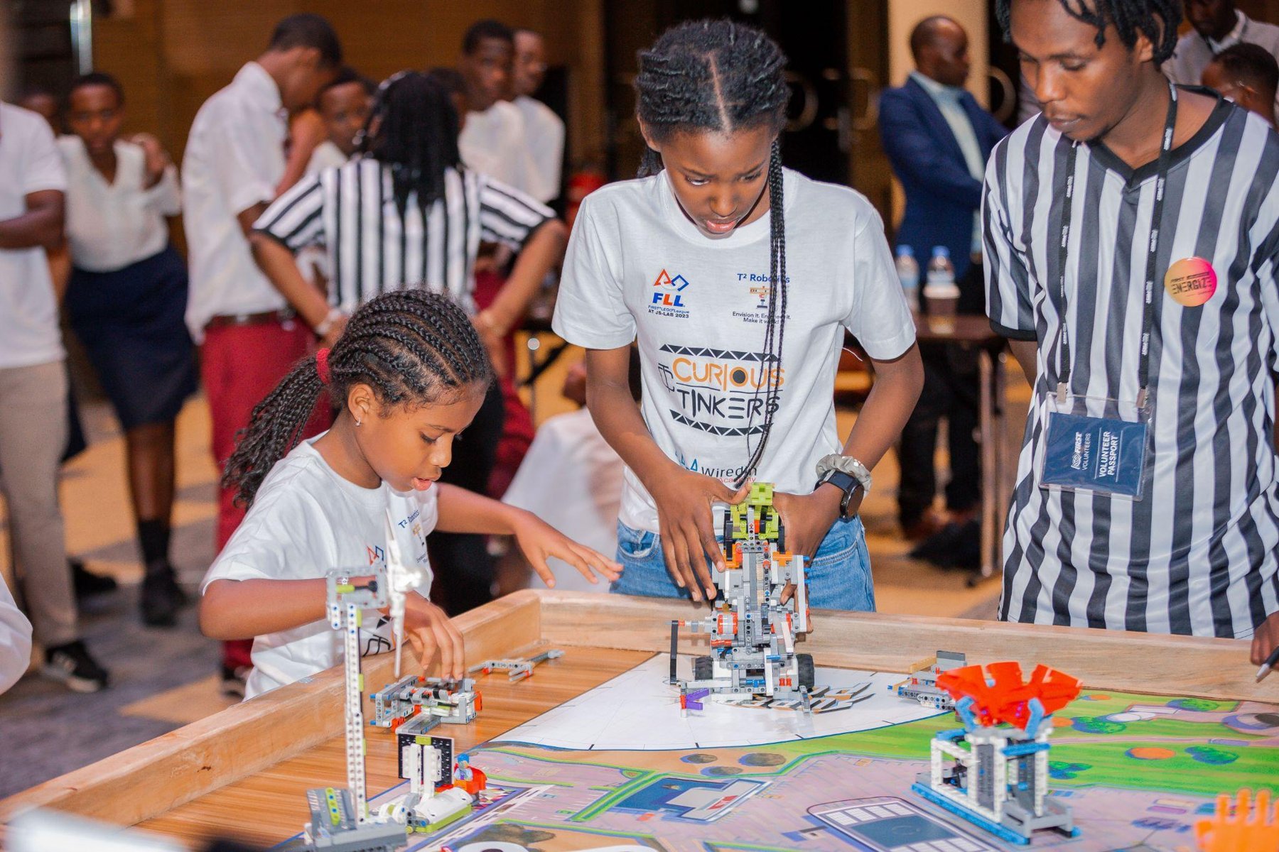 Students working with a FIRST LEGO League robot at a competition table